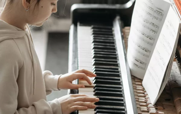 عازفة تعزف على البيانو من خلال النوتة الموسيقية