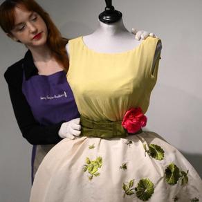 An employee poses with a Christian Dior dress worn by actress Elizabeth Taylor, and recently discovered with other dresses in a suitcase, ahead of their sale at Kerry Taylor Auctions, in London on November 25, 2022. A "lucky charm" Christian Dior dress worn by Elizabeth Taylor on the night she won best actress at the 1961 Oscars is to be sold at auction on December 6, 2022, after being stored in a suitcase in London for over 50 years. Daniel LEAL / AFP