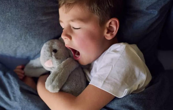صورة لطفل نائم  يحتضن لعبته