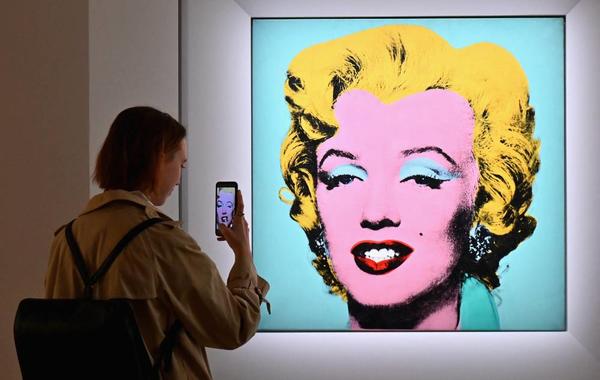A woman takes a photo of Andy Warhol's 'Shot Sage Blue Marilyn' during Christie's 20th and 21st Century Art press preview at Christie's New York on April 29, 2022 in New York City. Angela Weiss / AFP