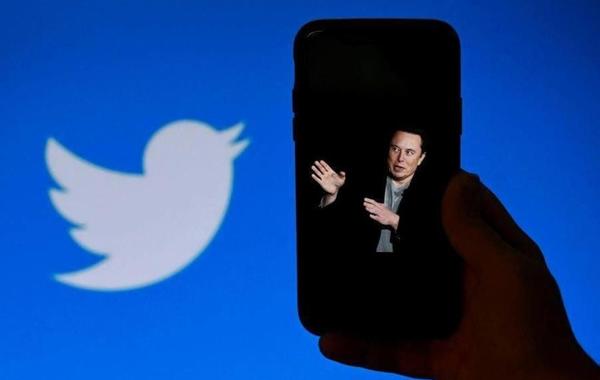 a photo of Elon Musk with the Twitter logo shown in the background, on October 4, 2022, in Washington, OLIVIER DOULIERY / AFP