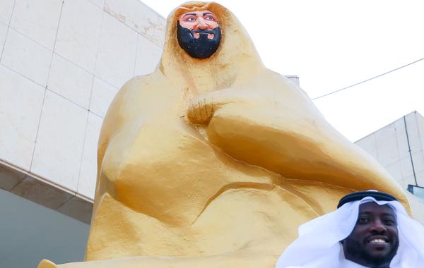 الفنان التشكيلي والنحات هاشم الجمعان يقف بجانب مجسم "محور العز" الذي قام بانجازة