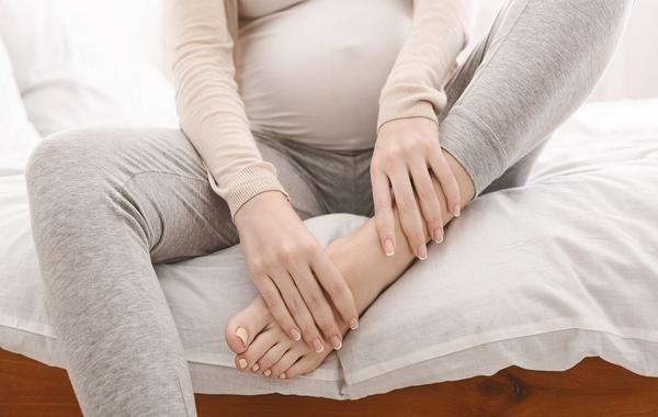 صورة لامرأة حامل تمسك قدمها